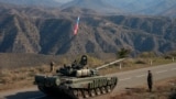 Servicemen from Russian peacekeeping troops stand next to a tank near the Armenian border following the signature of a November 9, 2020 deal to end the military conflict between Azerbaijan and ethnic Armenian forces in the breakaway region of Nagorno-Karabakh. 